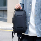 Person holding a dark combination lock chest bag by its top handle