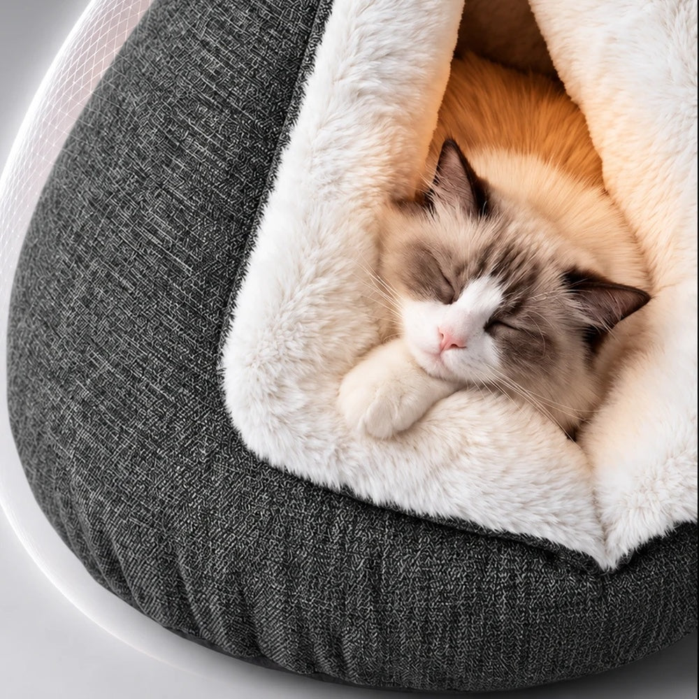 Brown-and-white cat resting inside a gray triangular cat cave bed with white plush lining, shown with Spanish on-screen captions.