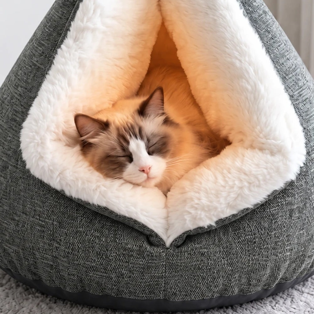 Brown-and-white cat resting and yawning inside a gray triangular cat cave bed with white plush lining and English on-screen captions.